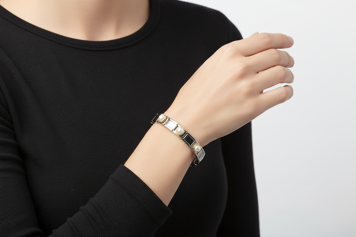 Bracelete metálico prateado com pérolas falsas no pulso de mulher com manga preta