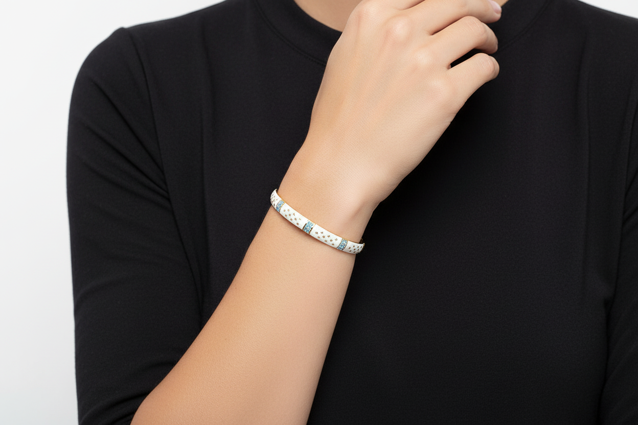 Pulseira rígida branca com detalhes azuis e dourados no pulso