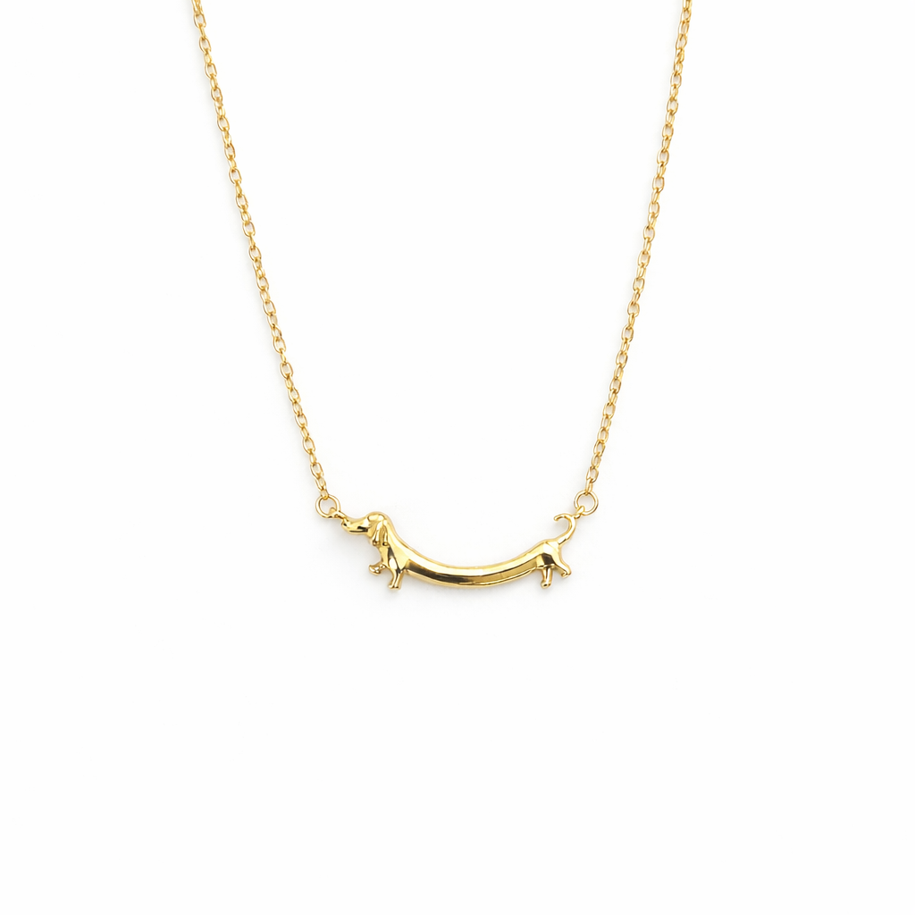 Colar dourado com pendente em forma de cão Dachshund sobre fundo branco