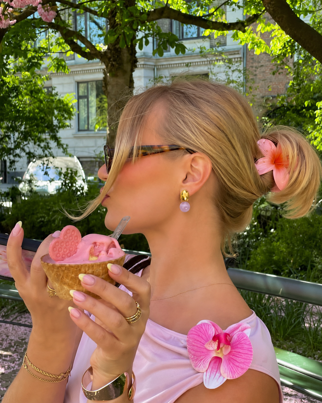 Mulher loira com óculos e gelado rosa ao ar livre