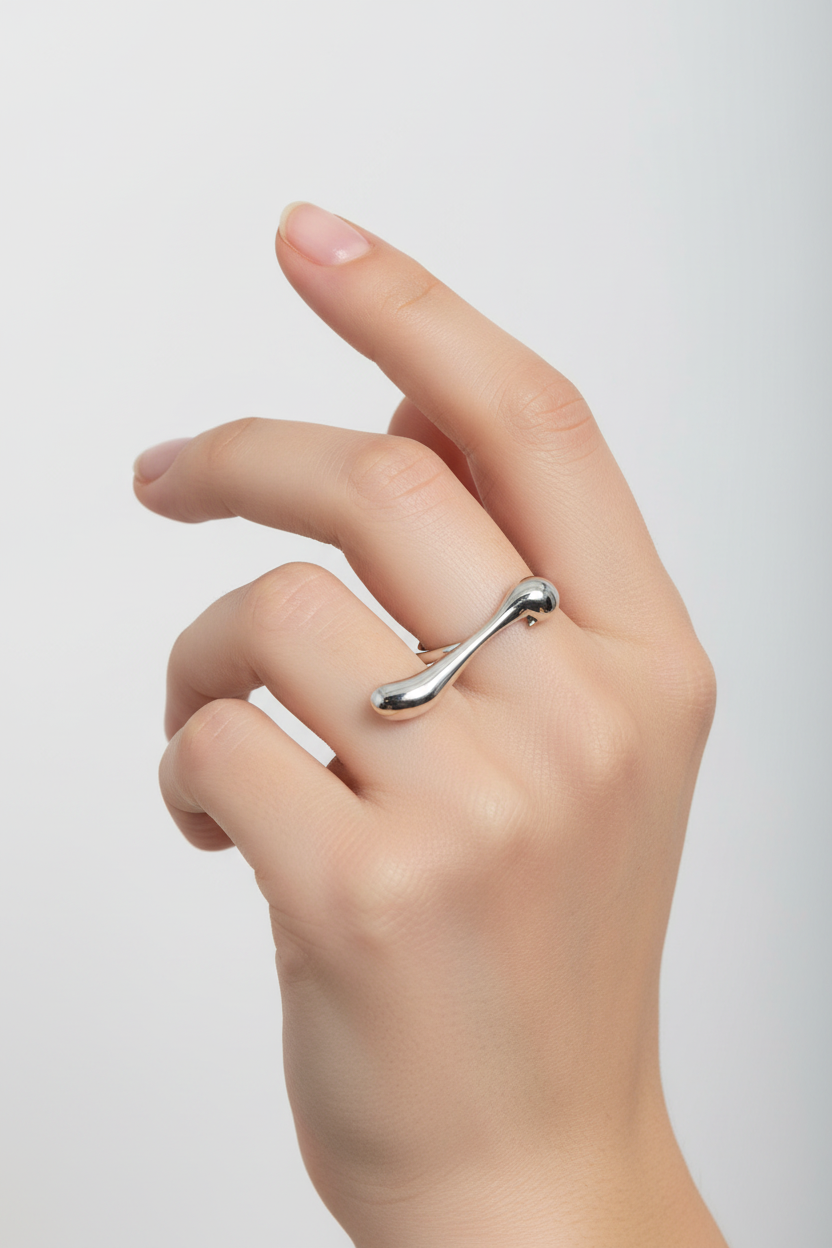 Anel prateado moderno numa mão feminina com fundo branco