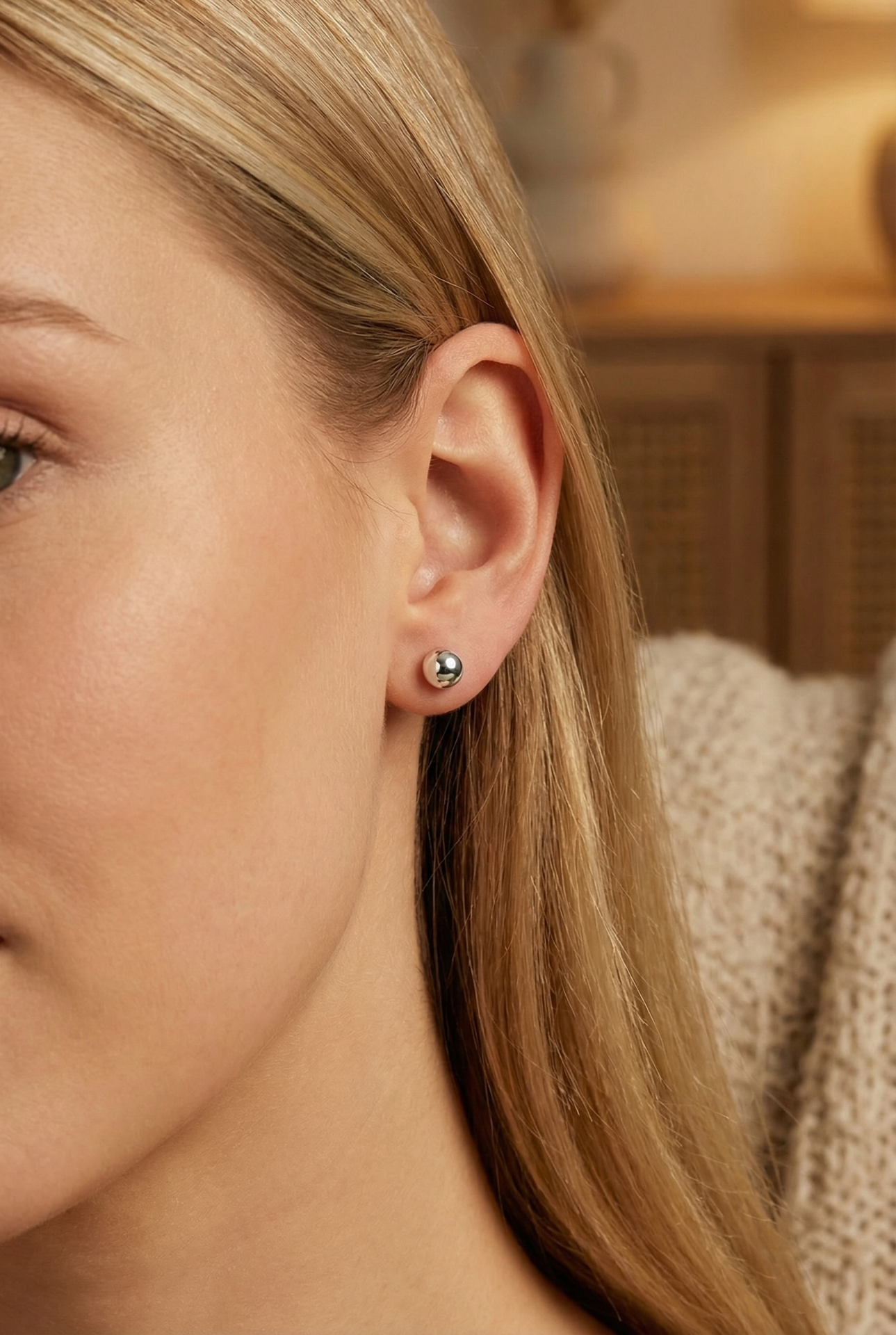 Brinco bola metálica prateada no lóbulo de orelha