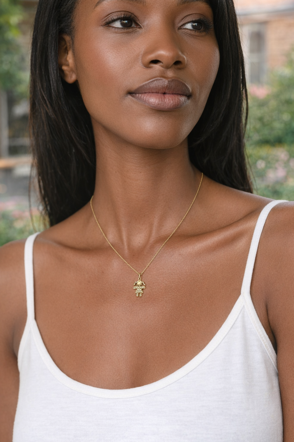 Mulher com colar dourado de pendente em forma de menina e top branco