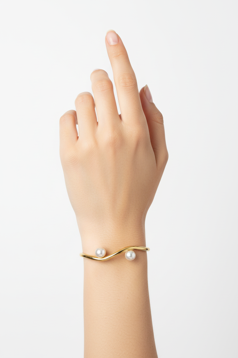 Pulseira dourada com pérolas no pulso de uma mão feminina