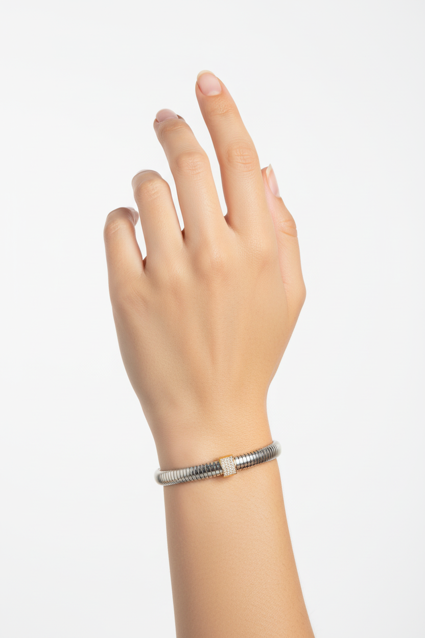 Pulseira prateada com detalhe dourado brilhante no pulso de uma mão