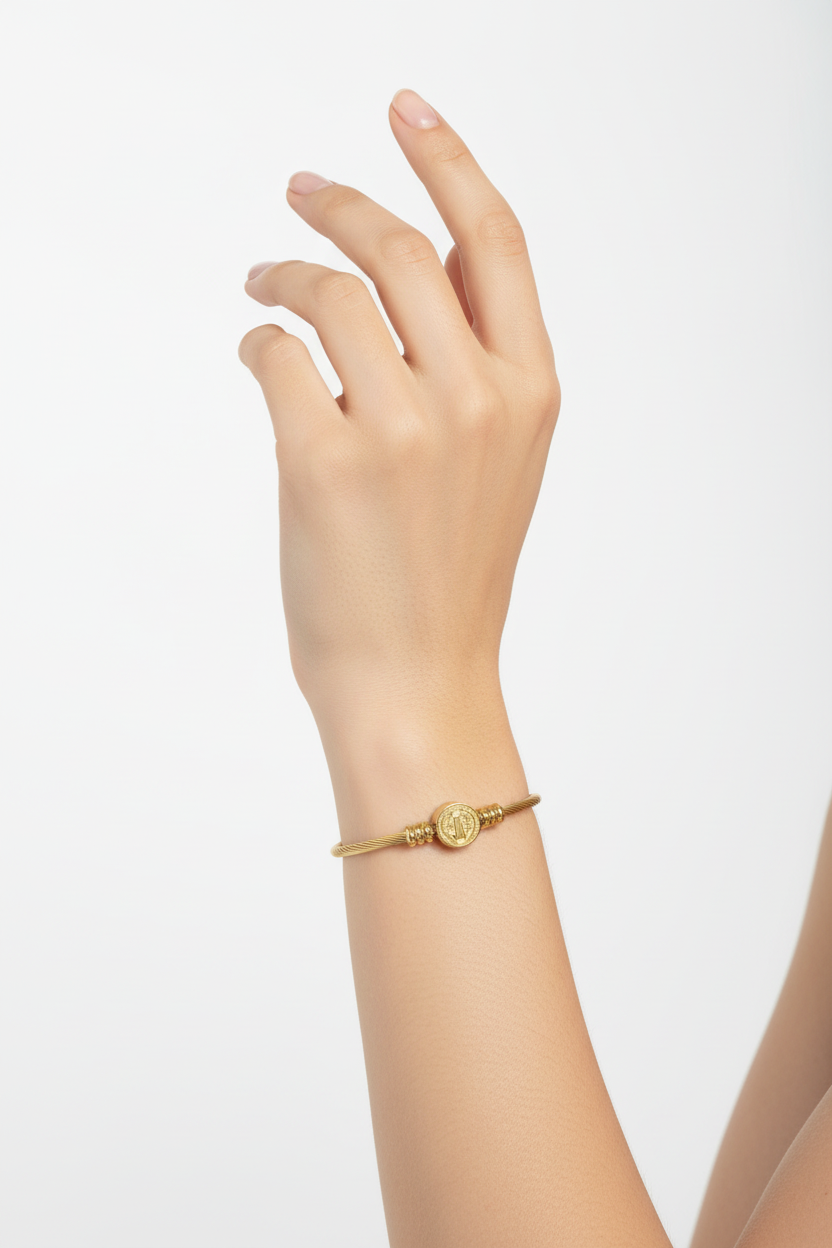 Pulseira dourada com fio torcido e elemento redondo ao centro no pulso