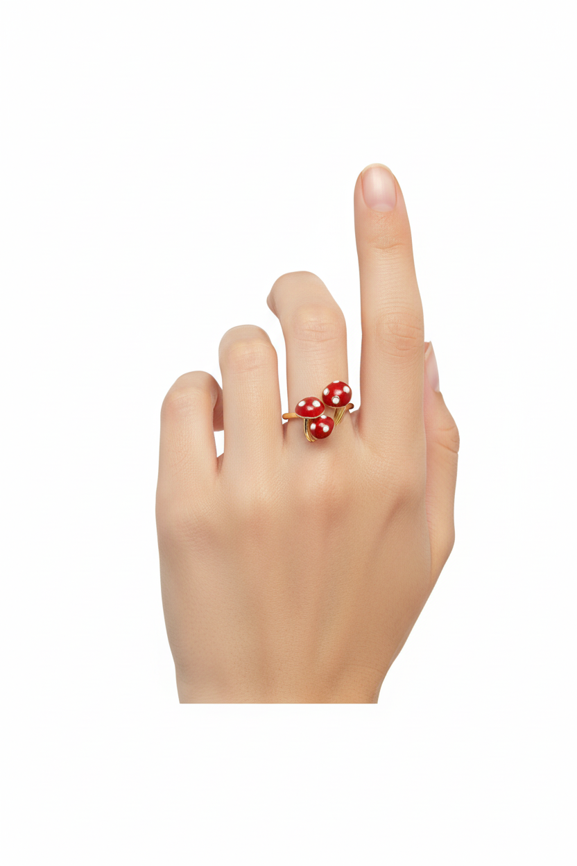 Anel dourado com três cogumelos vermelhos em mão feminina