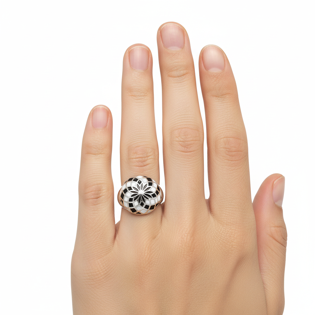 Anel prateado com padrão geométrico preto, branco e cinzento numa mão feminina.