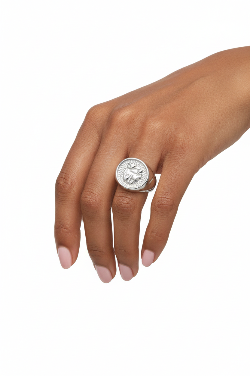 Anel de prata com figura em relevo num dedo de mão de pele morena