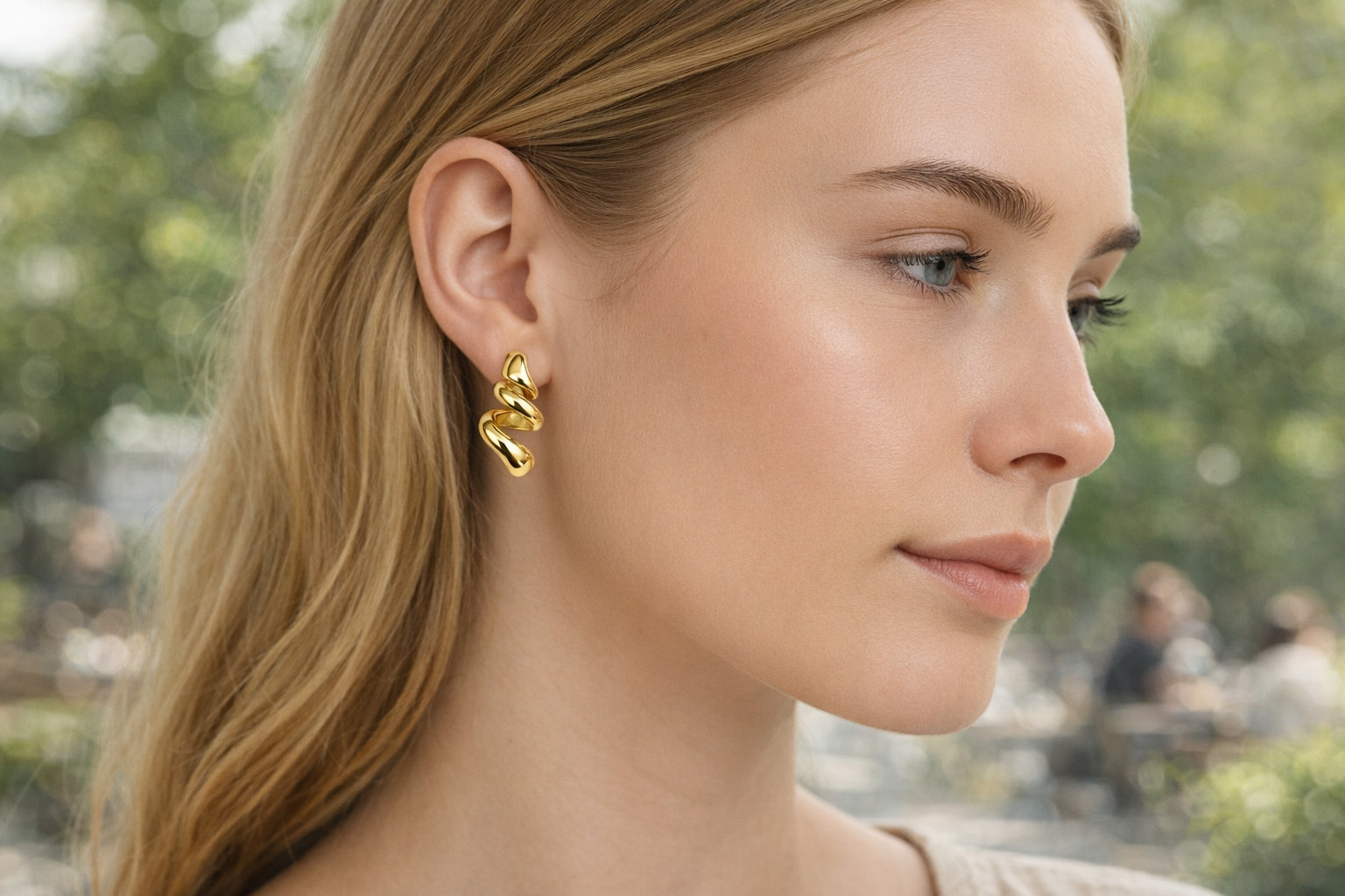 Brincos dourados espiral em mulher com cabelo loiro ao ar livre