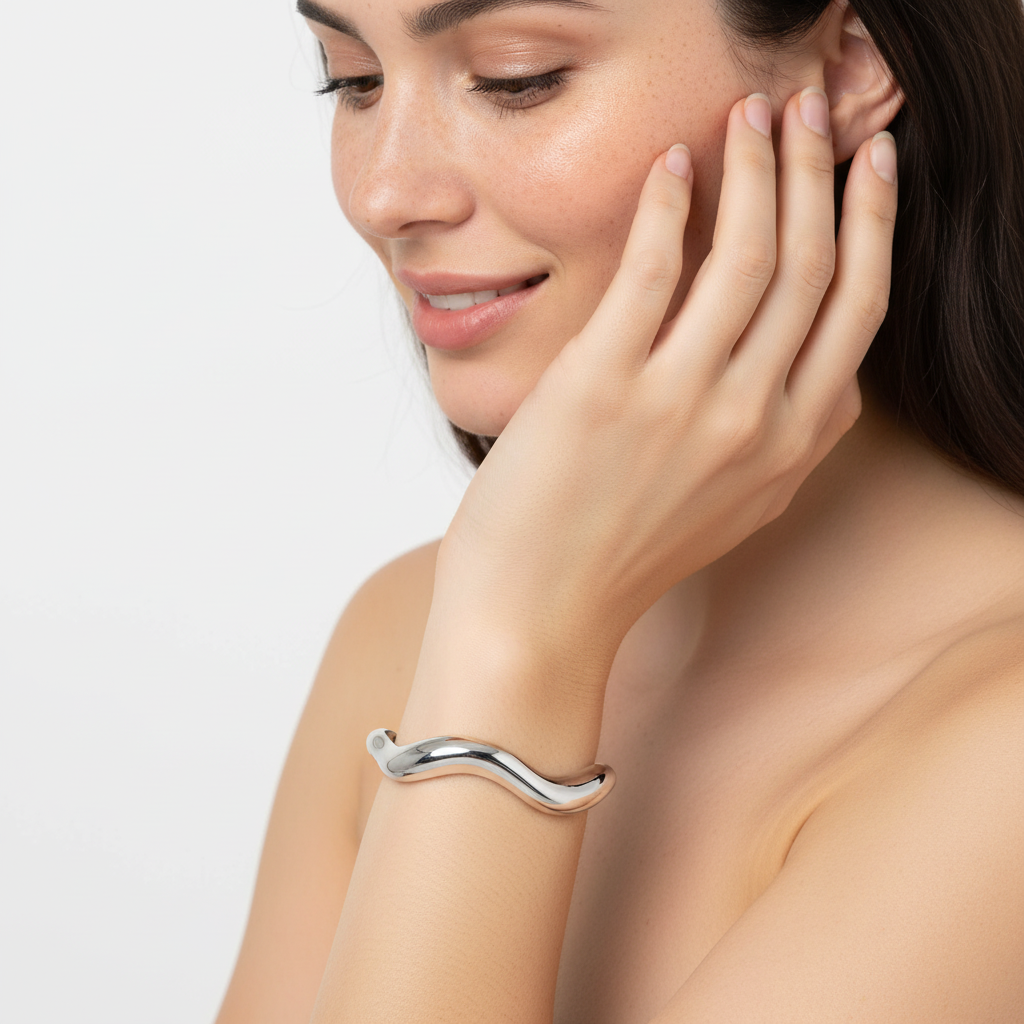 Pulseira prateada curva no pulso da mulher com fundo branco.