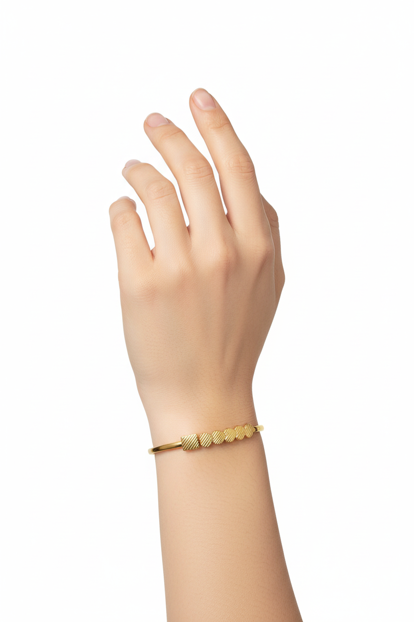 Pulseira dourada fina com detalhes circulares texturizados no pulso