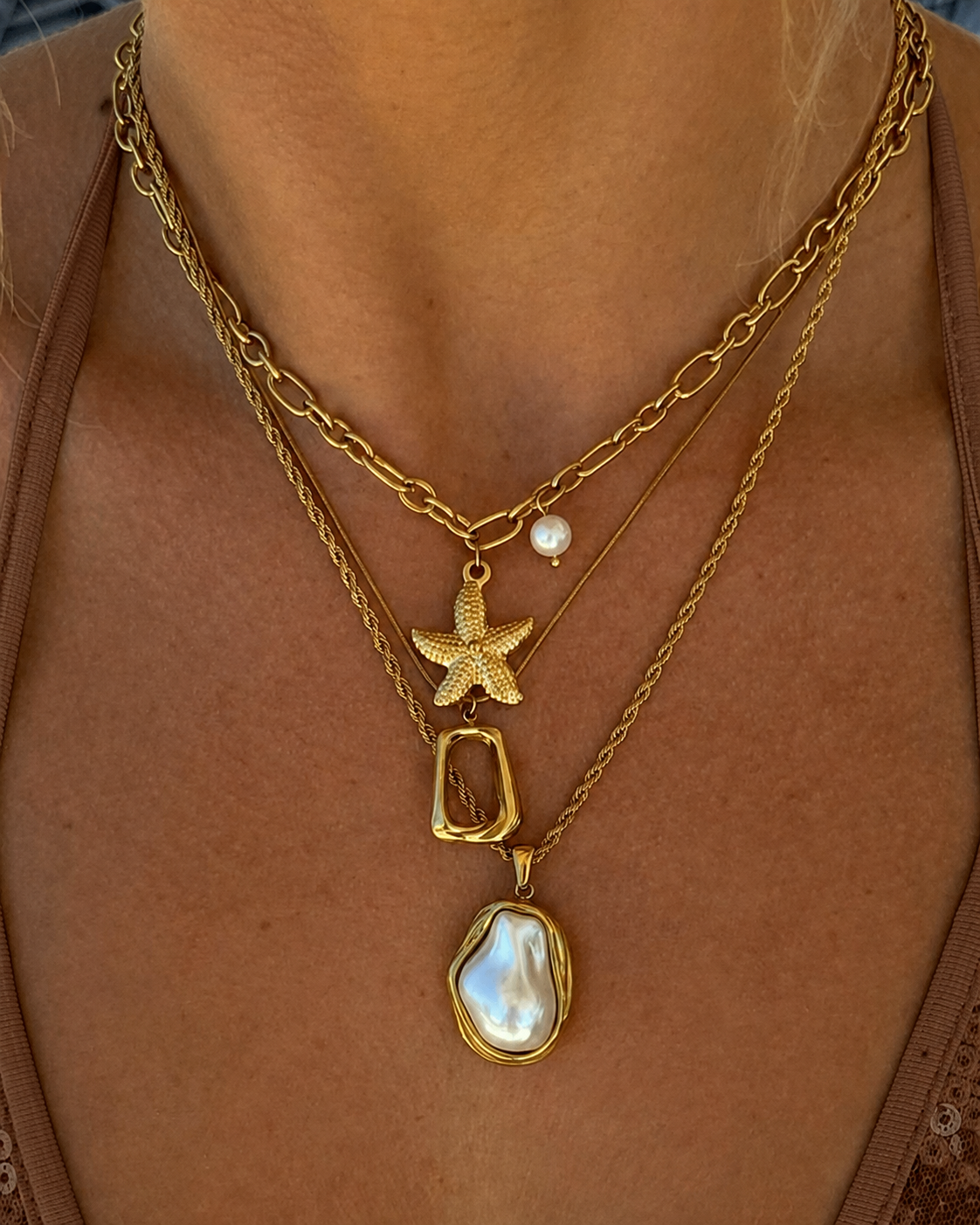 Colar dourado com pendentes de estrela-do-mar, pérola e madrepérola.