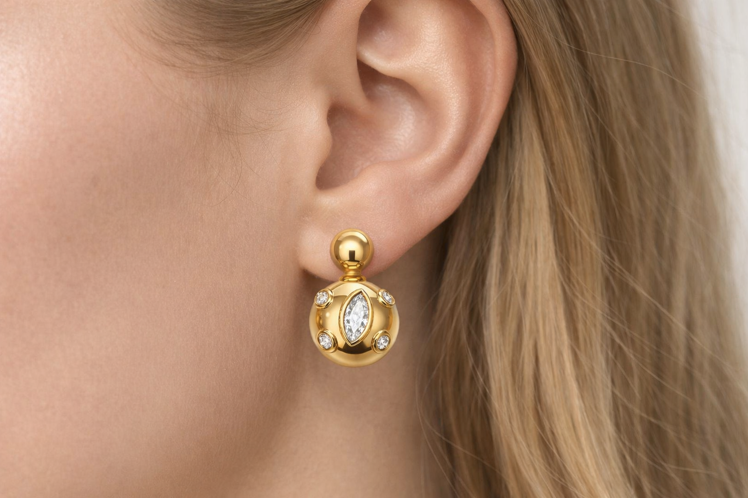 Brinco dourado com pedras brilhantes na orelha