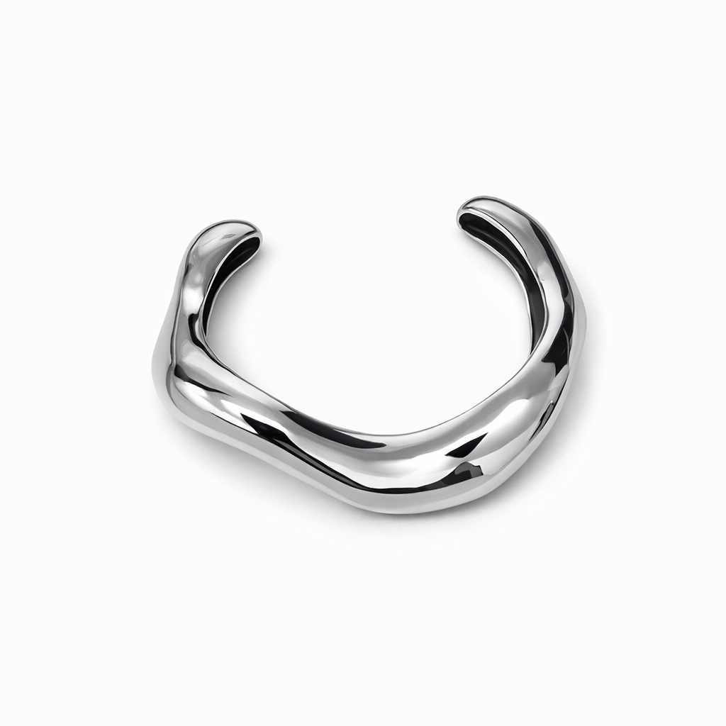 Pulseira metálica prateada com formato irregular sobre fundo branco