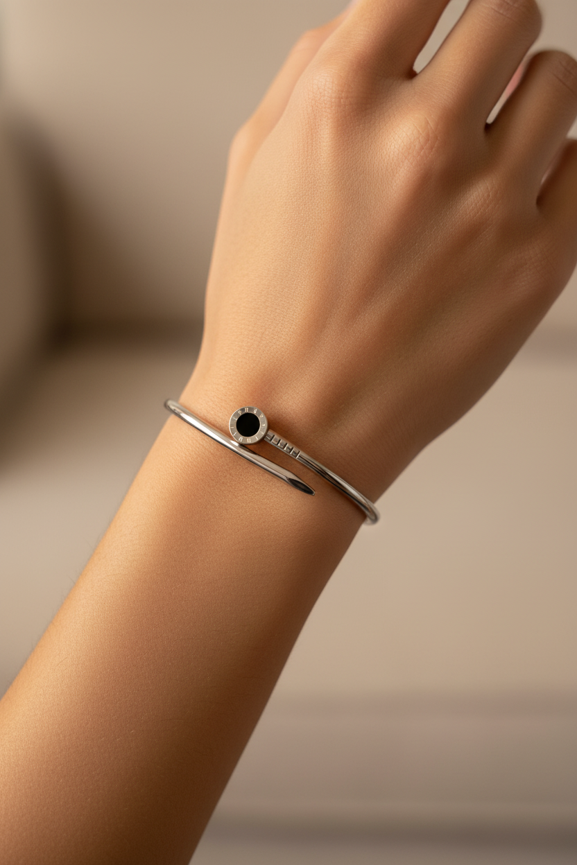 Pulseira prateada com detalhe preto em formato de prego no pulso