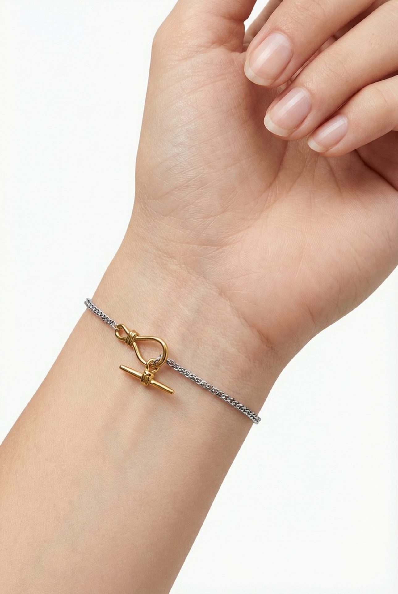 Pulseira com corrente prateada e fecho dourado no pulso