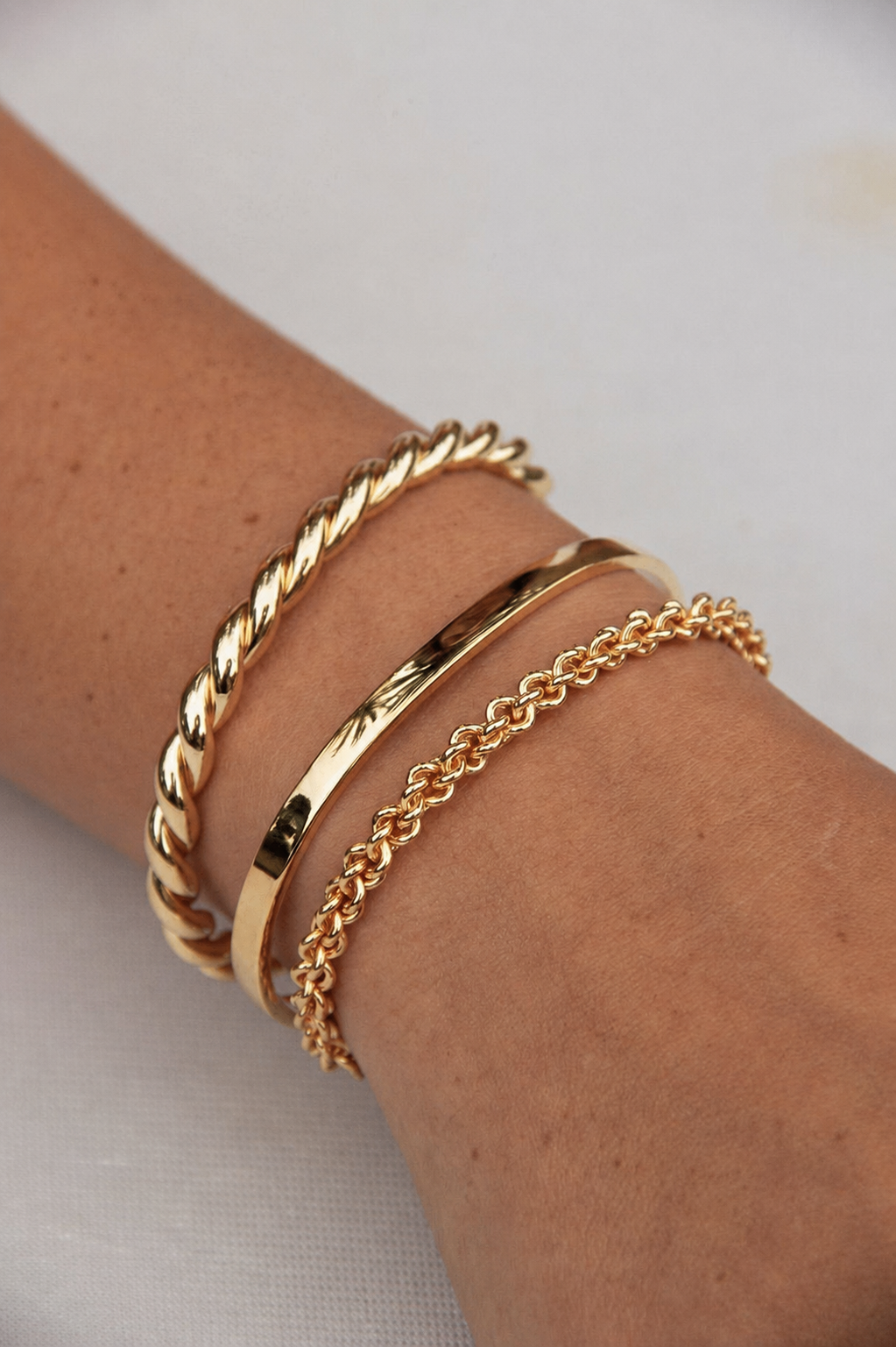 Três pulseiras douradas de metal no pulso