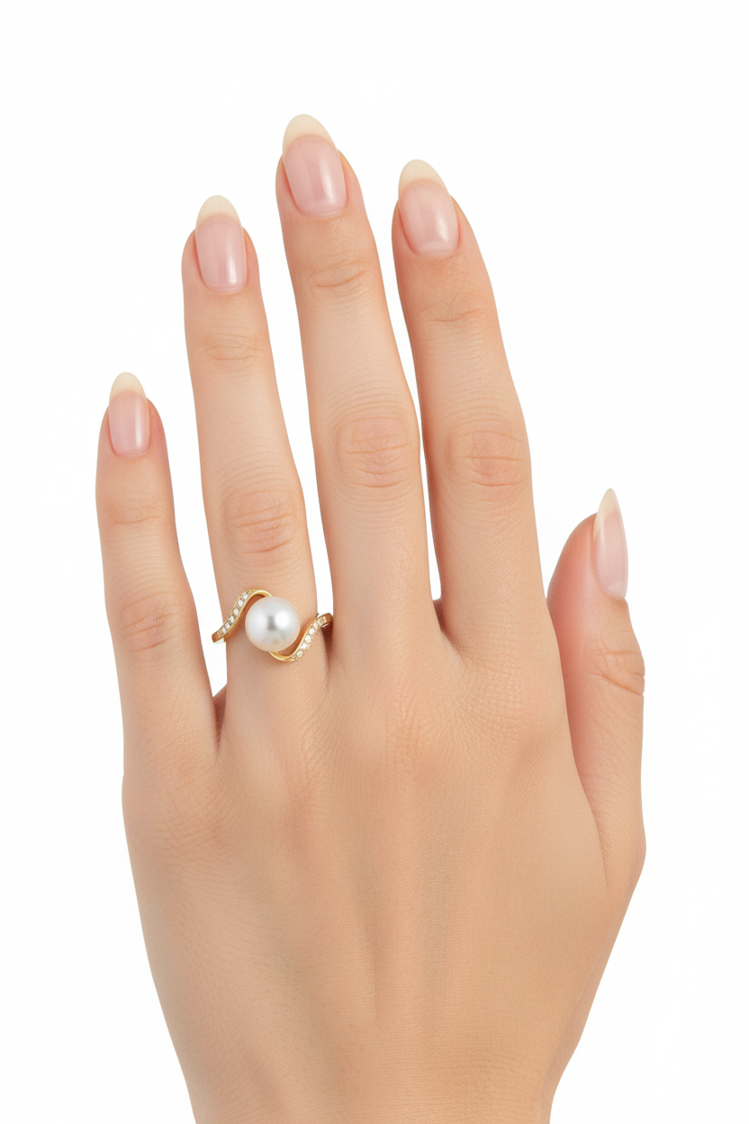 Mão feminina com anel dourado de pérola e pedras pequenas