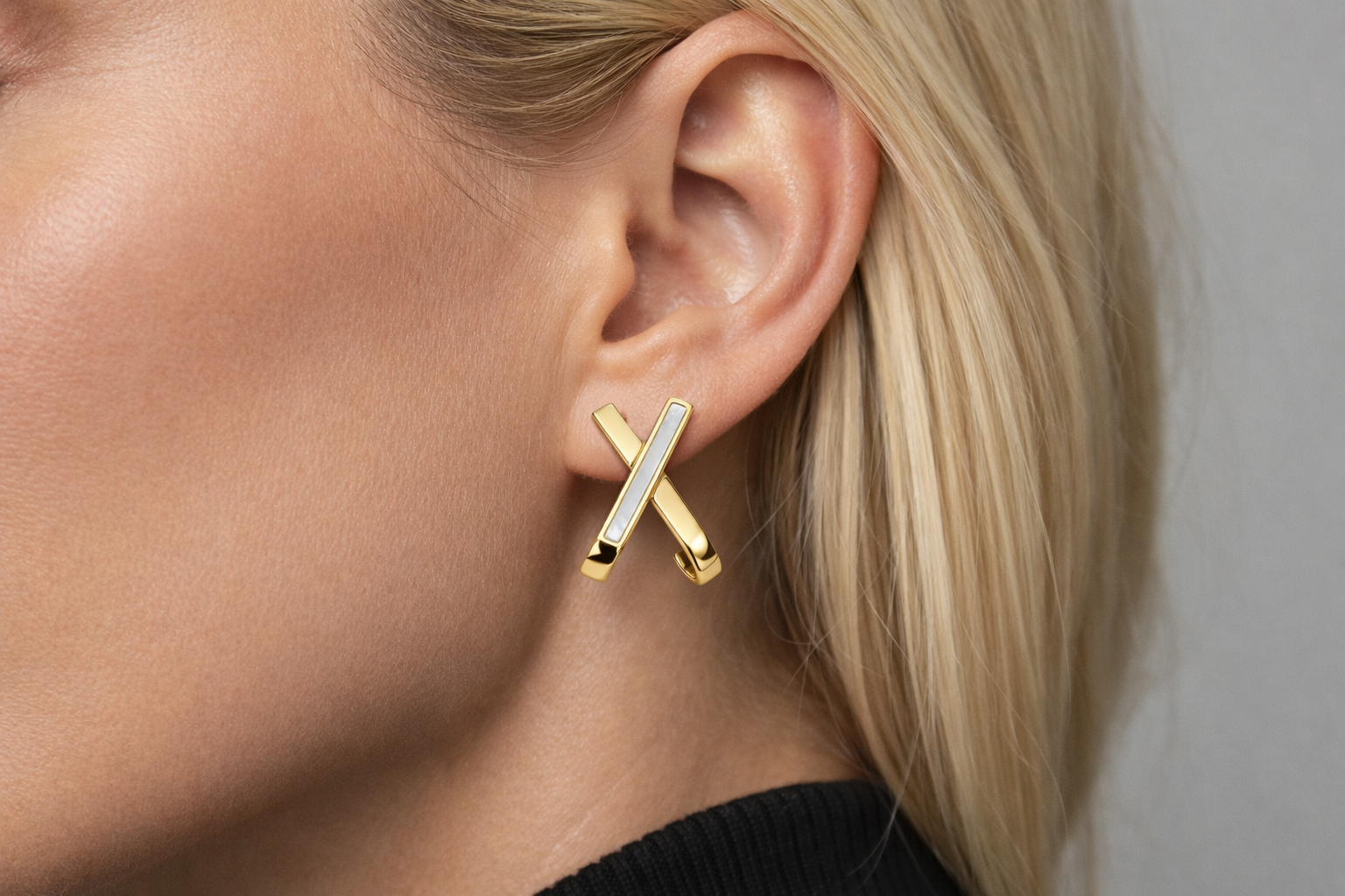 Brinco dourado em forma de X na orelha de mulher