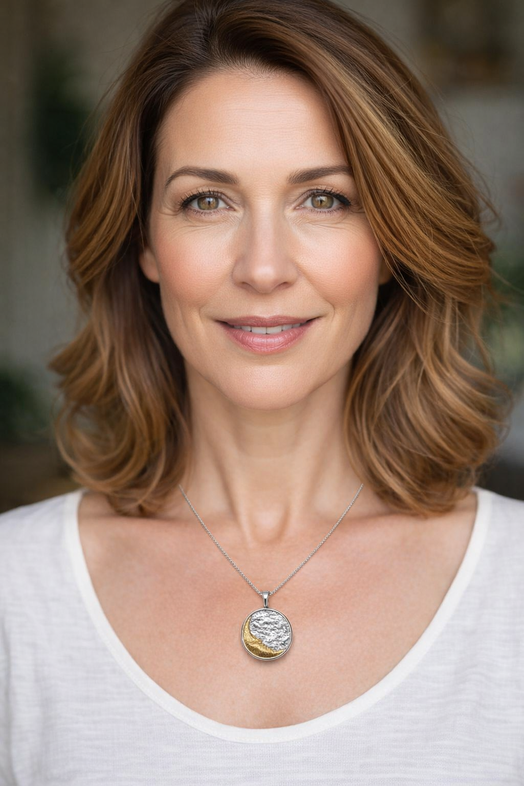 Colar com pendente redondo prata e dourado numa mulher com t-shirt branca