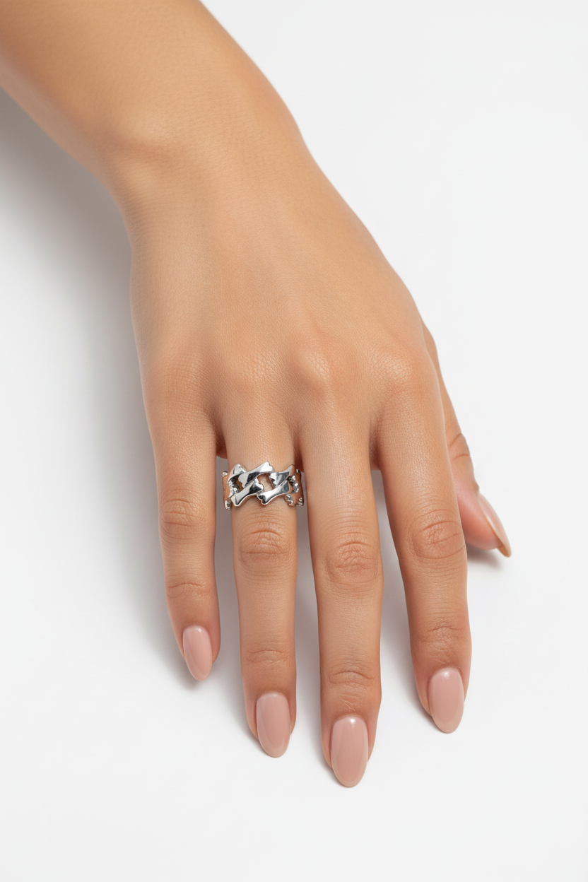 Mão feminina com anel de metal prateado entrelaçado e unhas nude