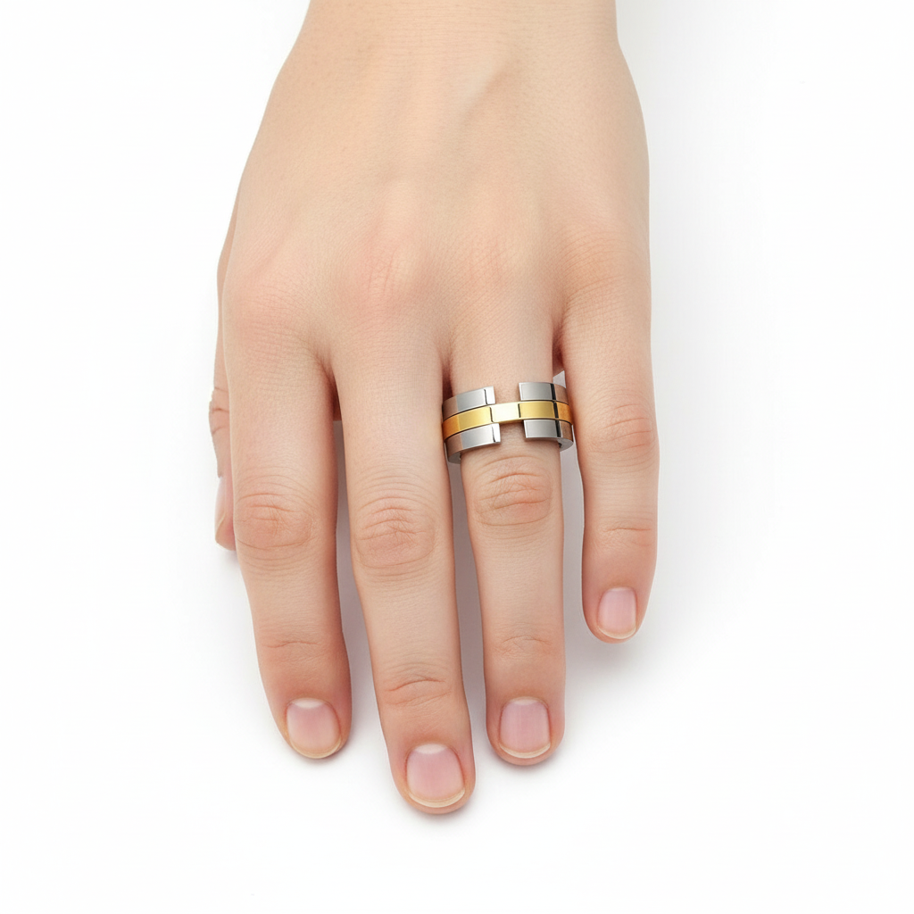 Anel moderno em metal prateado com detalhes dourados numa mão sobre fundo branco