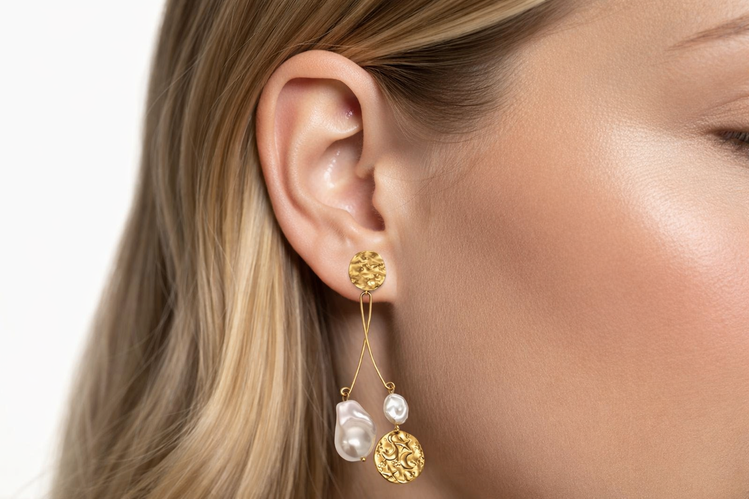 Brinco de metal dourado com pérolas orgânicas pendente no ouvido de uma mulher