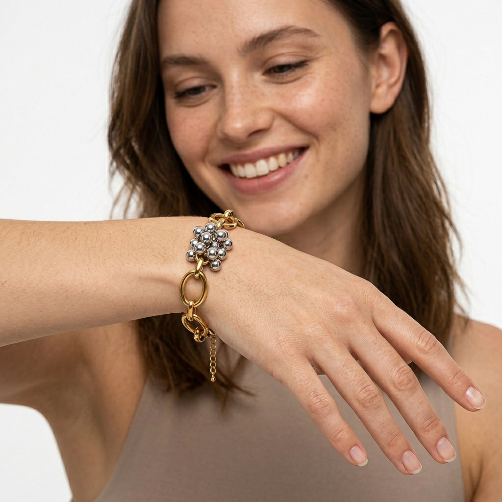 Bracelete dourado com elos grandes e esferas prateadas num braço feminino