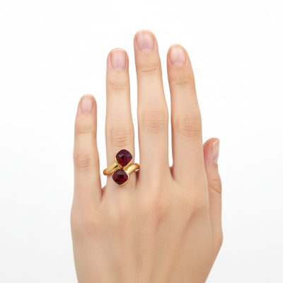 Mão feminina com anel dourado com pedras vermelhas.