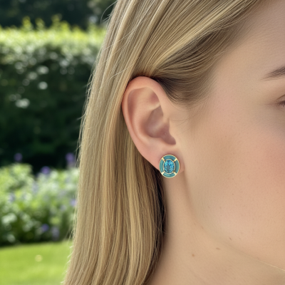 Brinco dourado com pedra azul e resina azul turquesa em orelha feminina, fundo jardim.