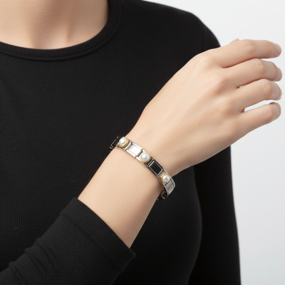 Bracelete metálico prateado com pérolas falsas no pulso de mulher com manga preta