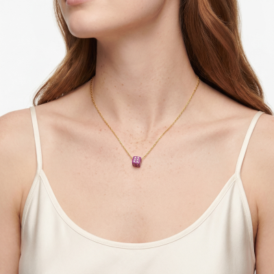 Colar dourado com pendente dado roxo em pescoço de mulher com vestido creme