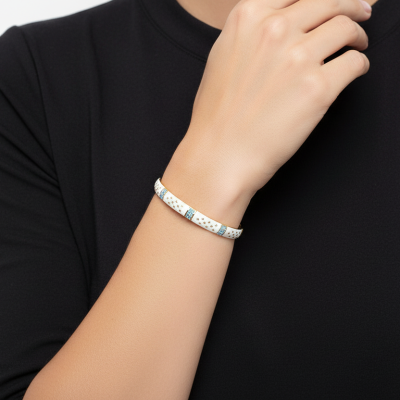 Pulseira rígida branca com detalhes azuis e dourados no pulso