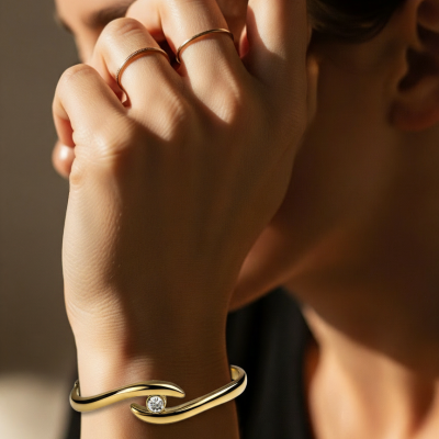 Pulseira dourada com pedra brilhante e duas argolas simples douradas num pulso de pele clara