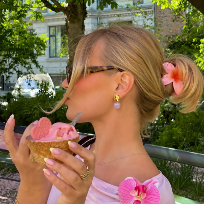 Mulher loira com óculos e gelado rosa ao ar livre
