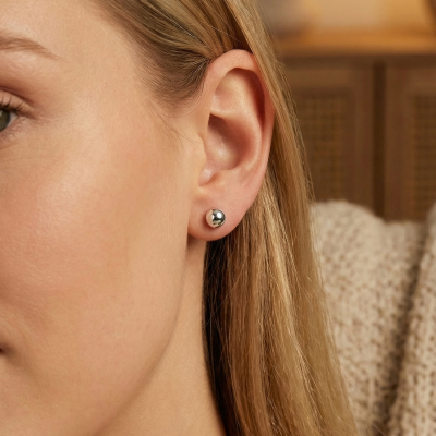 Brinco bola metálica prateada no lóbulo de orelha