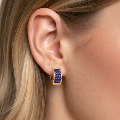 Brinco dourado com pedras azuis usado na orelha