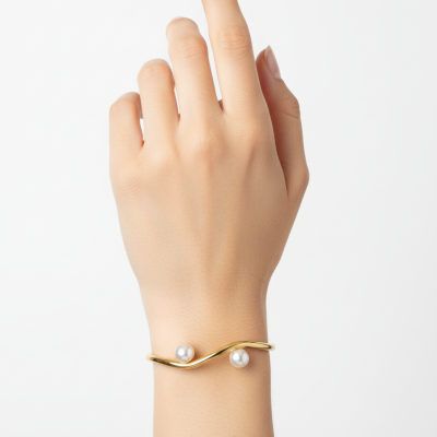 Pulseira dourada com pérolas no pulso de uma mão feminina