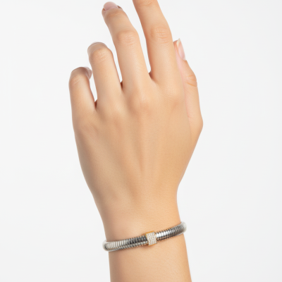 Pulseira prateada com detalhe dourado brilhante no pulso de uma mão