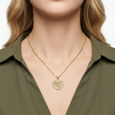Colar dourado com pendente em forma de coração e árvore, usado por modelo com camisa verde.