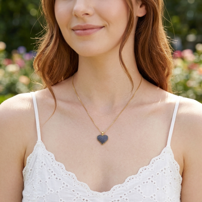 Colar dourado com pendente em coração azul no pescoço de mulher com vestido branco rendado