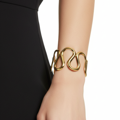 Pulseira dourada ondulada num pulso feminino com roupa preta.