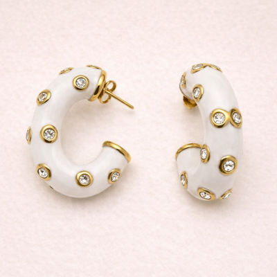 Brincos de argola brancos com detalhes dourados e pedras transparentes.