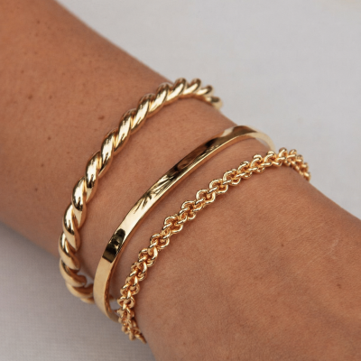 Três pulseiras douradas de metal no pulso