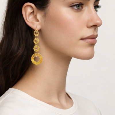 Brincos dourados em sequência de anéis concêntricos em modelo com t-shirt branca