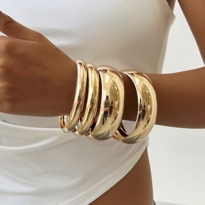 Braço com pulseiras douradas grossas