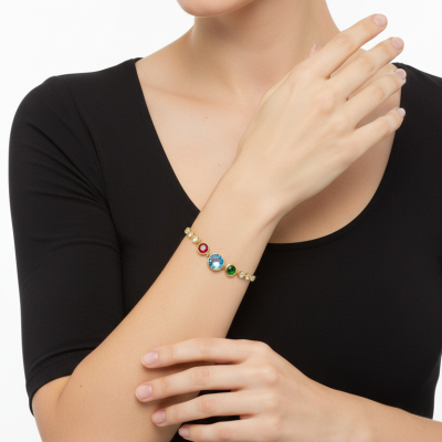 Pulseira dourada com pedras coloridas no braço de mulher com blusa preta