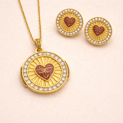 Conjunto de colar e brincos dourados com pedrinhas e coração vermelho no centro.