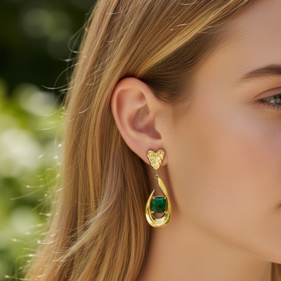 Brincos dourados com pedra verde usados por modelo.